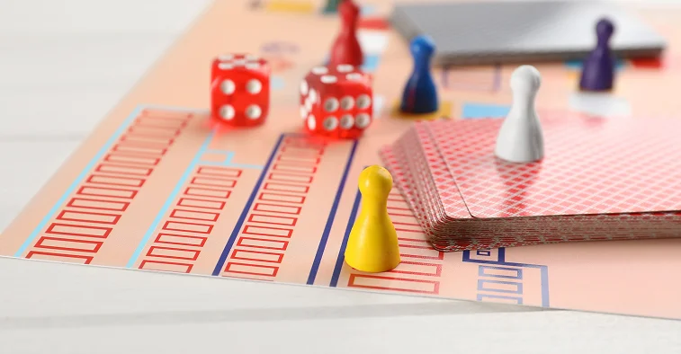 Een bordspel is opgezet met kleurrijke dobbelstenen, speelstukken, kaarten en een speelbord, helemaal klaar voor een spelletje aan tafel.